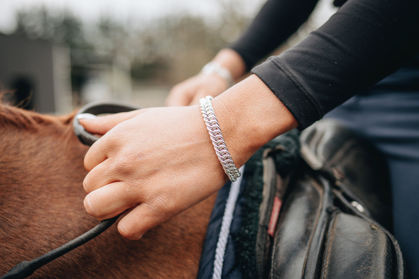 An equestrian riding a horse wearing the original Crawford Hill Curb Chain Bracelet.