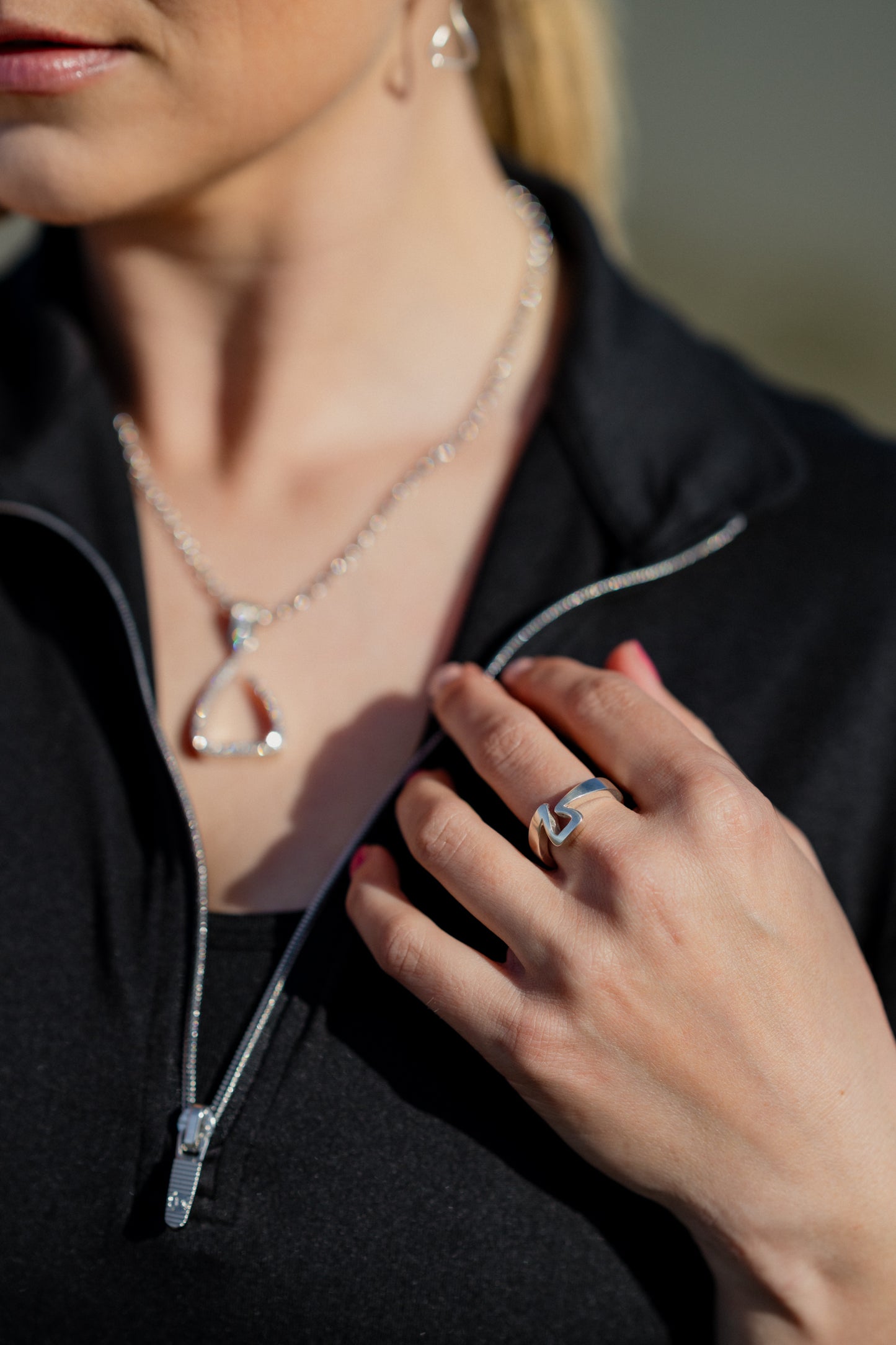 An equestrian wearing a Crawford Hill Jump Ring. The Jump ring pays homage to the iconic Free Jump Stirrup. In the background, you can see her wearing the white gold Jump Pendant fully set with 1/2 a carat of brilliant cut round diamonds.