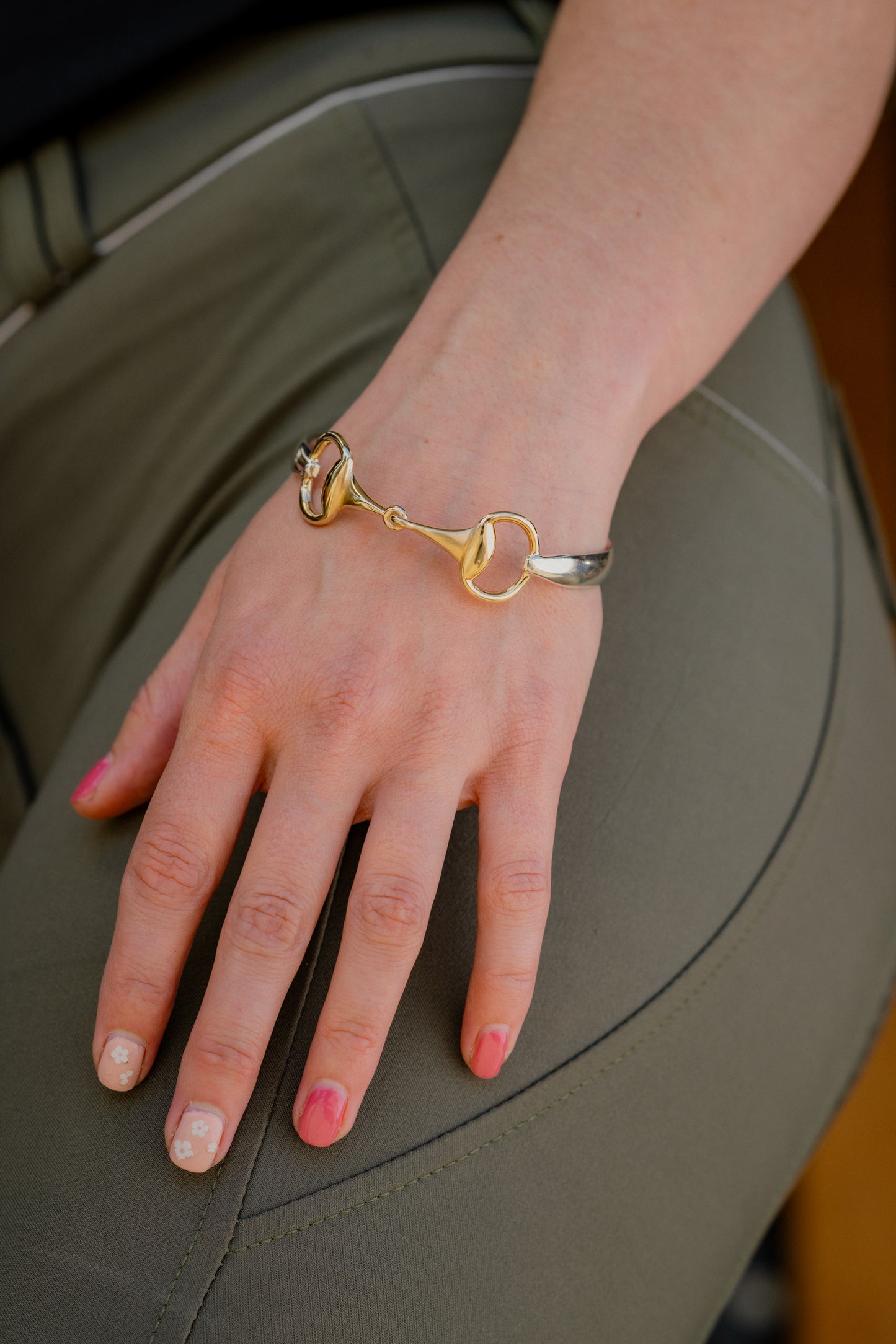 An equestrian wearing a two tone snaffle bangle. The snaffle is a solid 9ct yellow gold, and the band in sterling silver.
