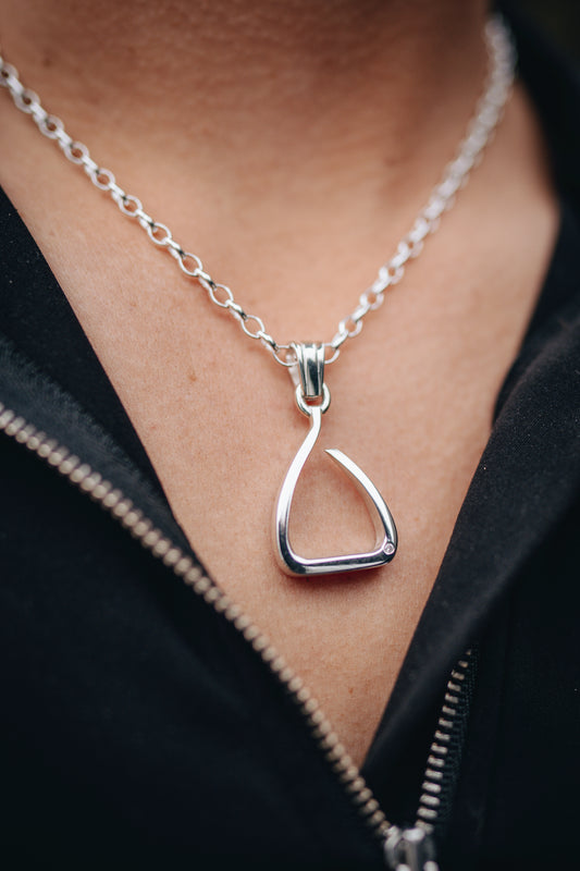 An equestrian wearing the orgional Crawford Hill sterling silver jump pendant. Crafted to pay homage to the "Free Jump Stirrup" this unique piece of jewellery embodies the BOLD. Worn on a sterling silver lightweight oval belcher chain.