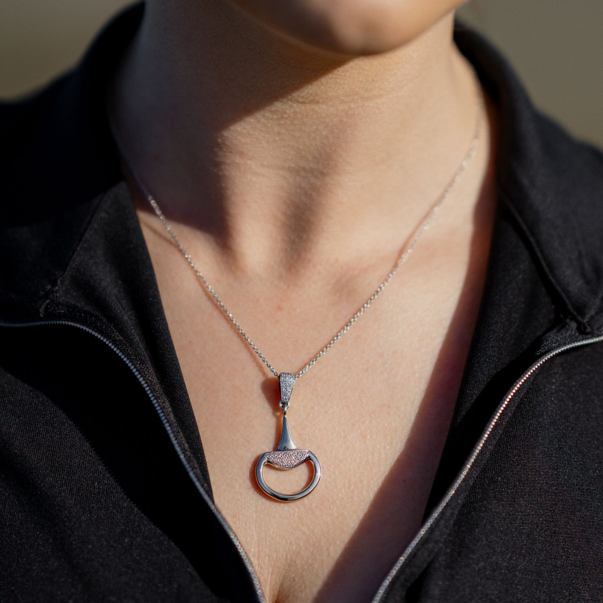 Equestrian wearing a white gold diamond set half snaffle pendant by Crawford Hill.