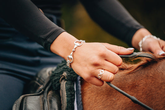 An equestrian riding a horse wearing the popular Snaffle and Curb Chain Bracelet in sterling silver featuring a sterling silver snaffle ring