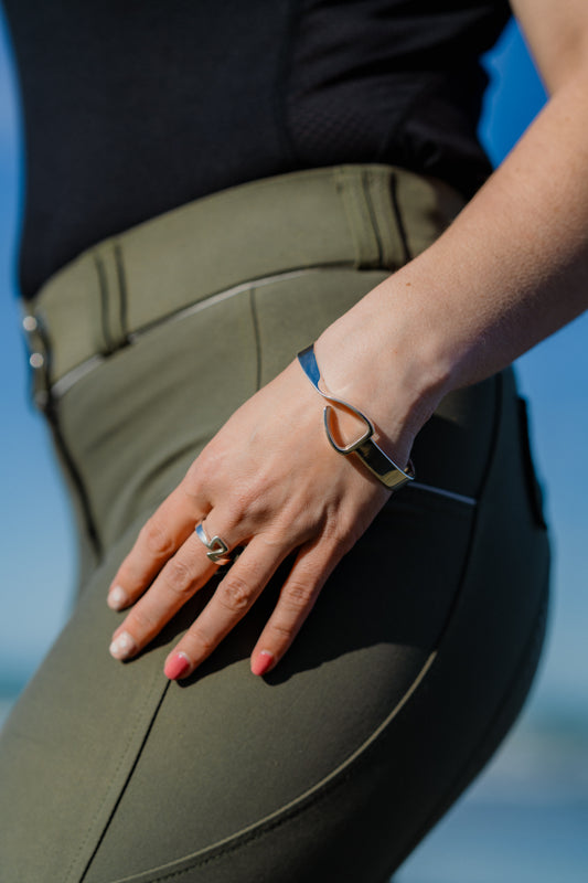 Equestrian wearing the Crawford Hill Jump Stirrup Bangle. This bangle is unique in its design with a twist in the band. 